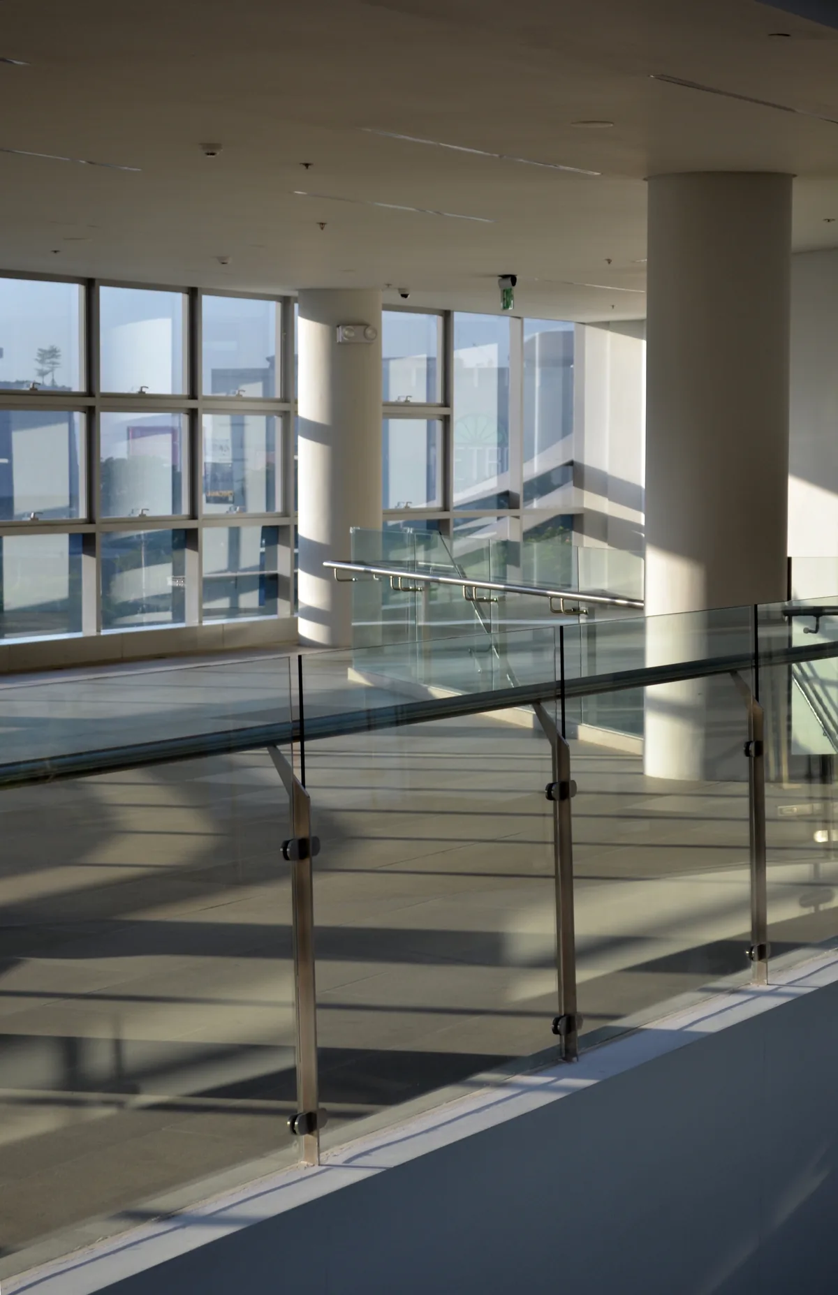 Guarda-corpo de vidro com corrimão de inox em interior moderno com colunas