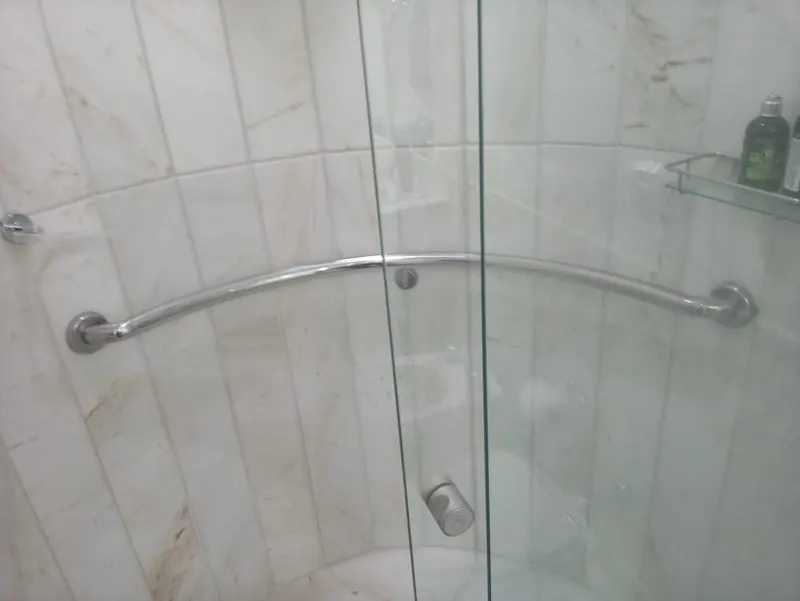 Barra de apoio curva em aço inox instalada em banheiro