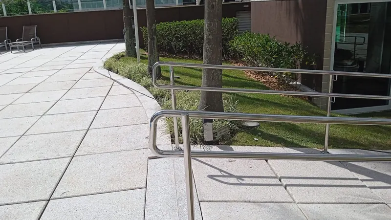 Corrimão de aço inox curvo em área externa de condomínio em Belo Horizonte