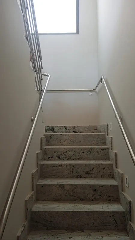 Corrimão de inox em escada interna com degraus de granito