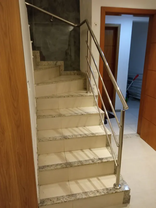 Corrimão de inox em escada interna com acabamento em madeira