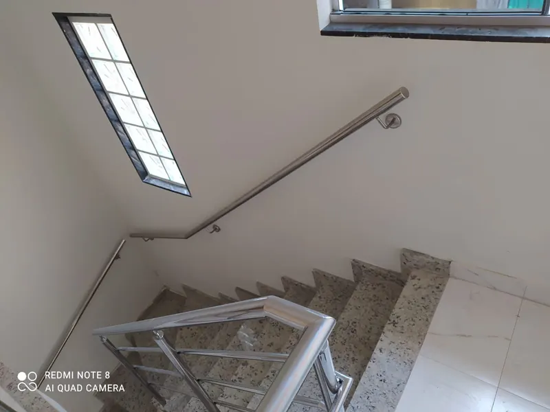 Corrimão de parede em inox acompanhando lance de escada