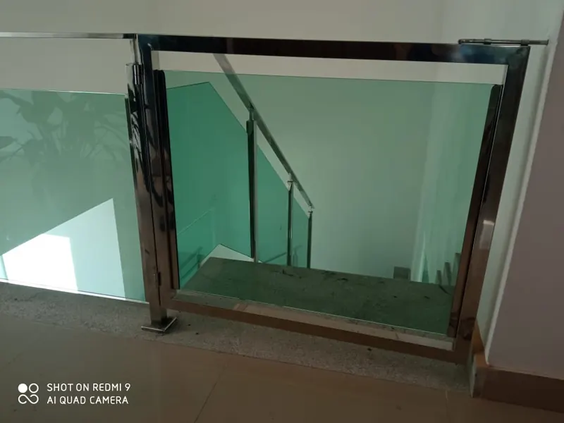 Guarda-corpo de vidro verde com prumos de inox em ambiente interno